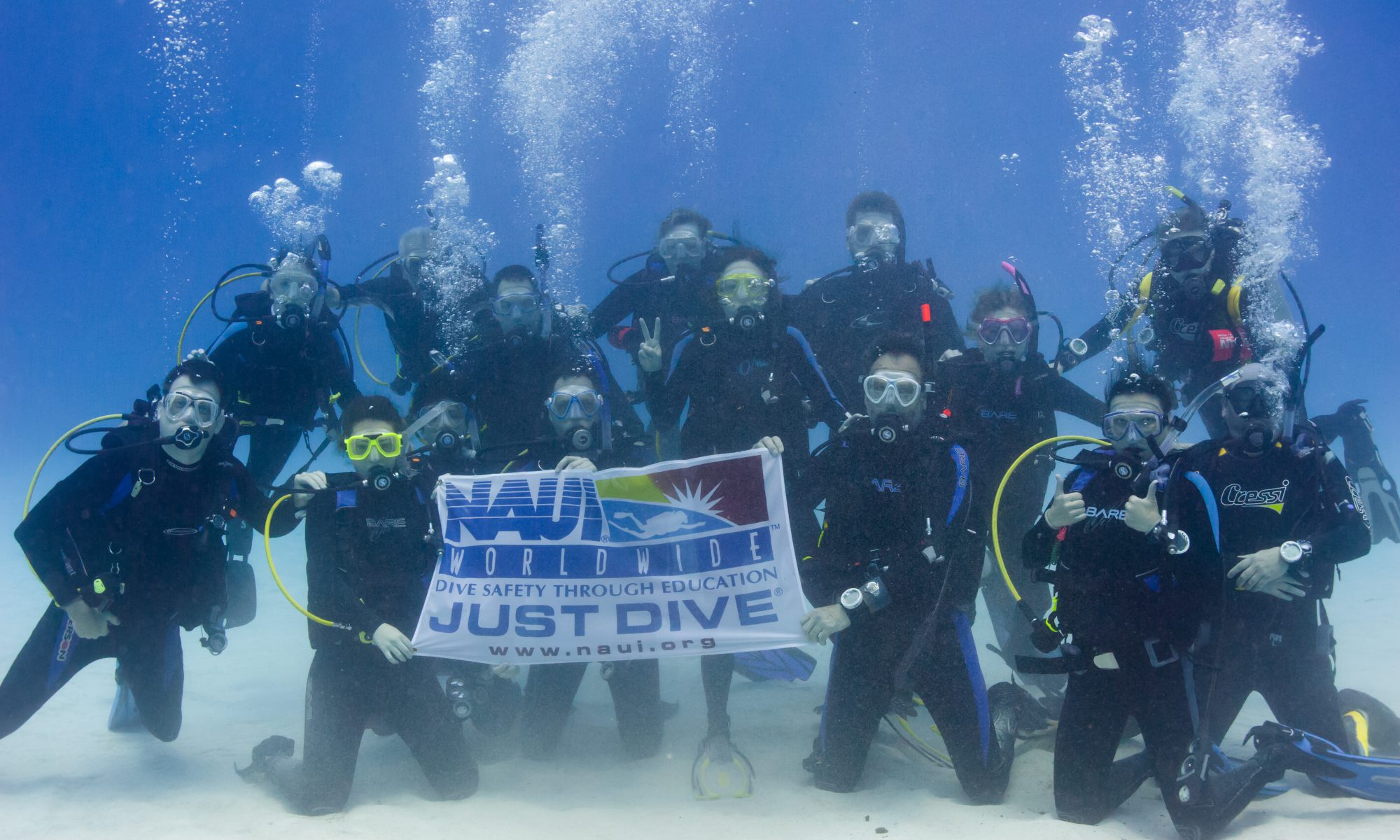 HHUC group shot underwater of Divers, with NAUI banner, in Little Cayman. Photo credit: Courtney Gibson